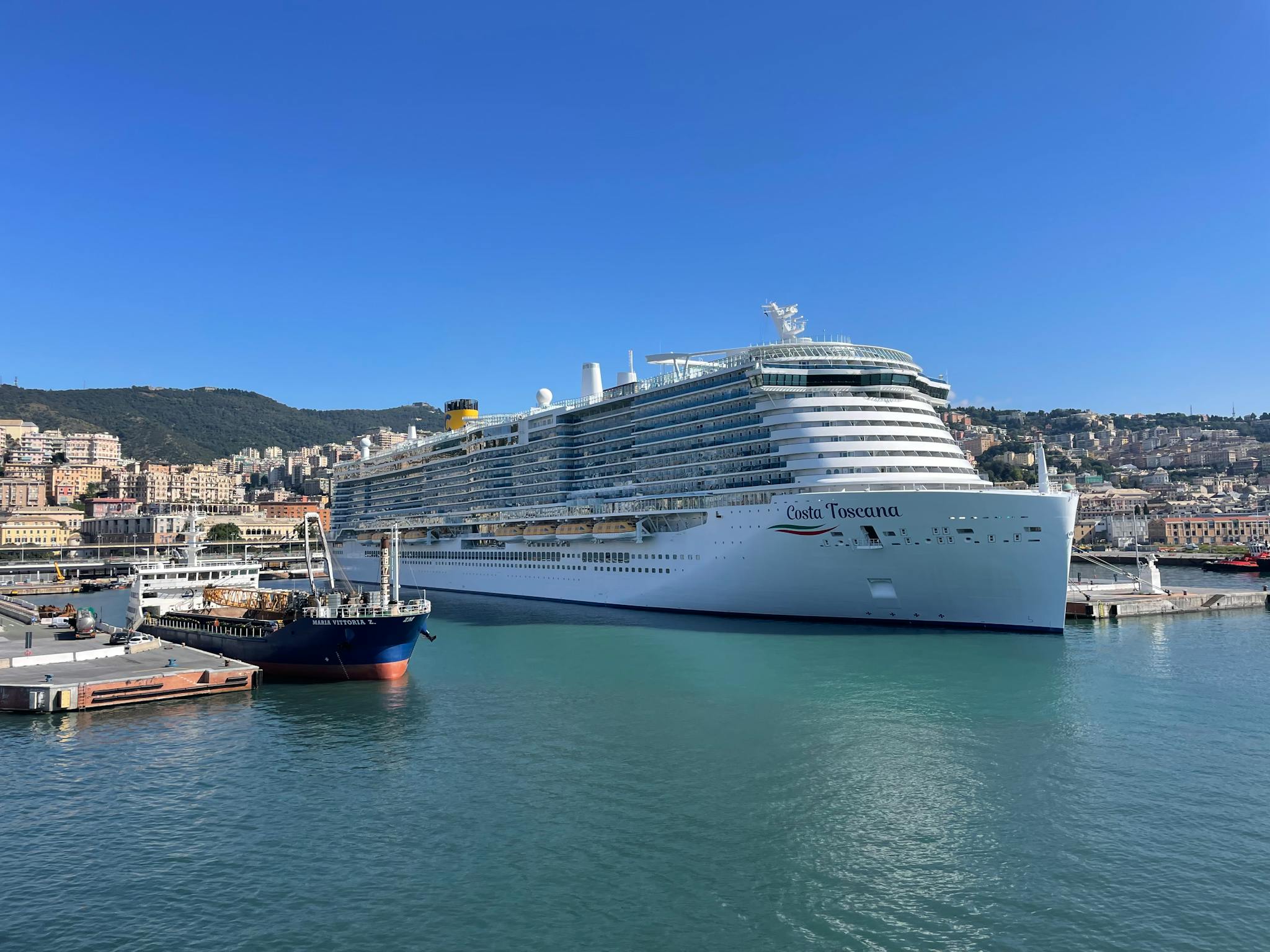 A luxurious cruise ship docked at a scenic coastal harbor on a sunny day, perfect for relaxation and travel enthusiasts.