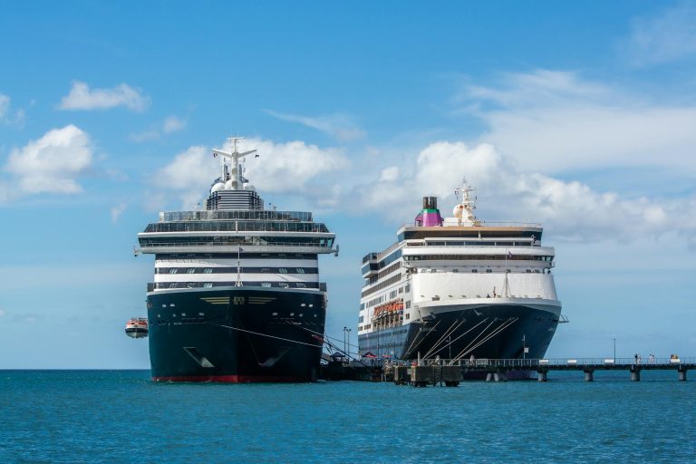 Two large cruise ships docked at a pier under clear blue skies, ideal for travel and tourism visuals.