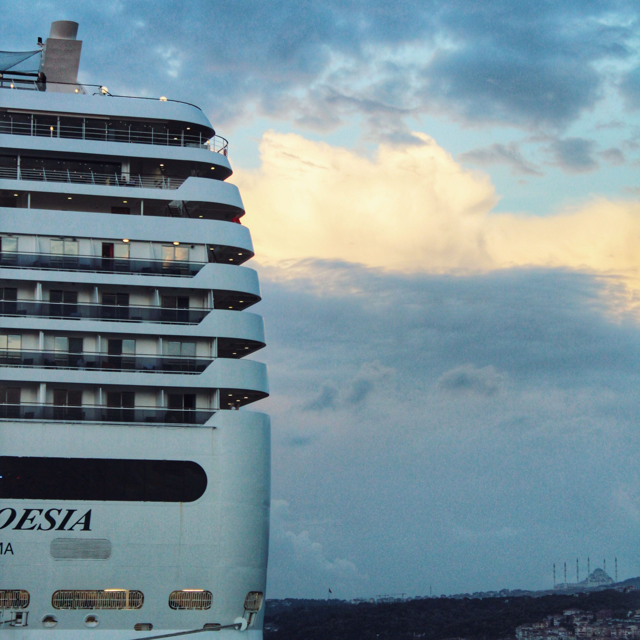 A close-up view of the white stern (aft) of the MSC Cruises ship, MSC Poesia, sailing in Istanbul, Turkey at sunset, with the ship's name clearly emblazoned across the rear hull above the mooring ports.